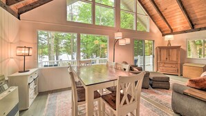 A spacious room with a high ceiling, large windows, a dining table, and a cozy seating area. - Maine Lakefront Escape: Dock, Watercraft, Fire Pit (Limerick)