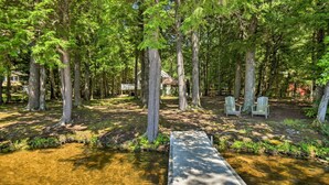 A wooden deck leading to a small house surrounded by tall trees. - Maine Lakefront Escape: Dock, Watercraft, Fire Pit (Limerick)