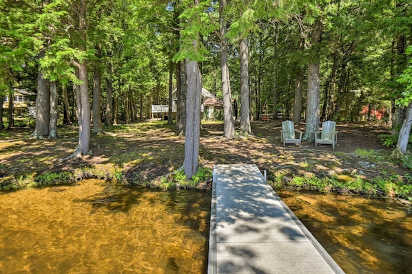 A wooden deck leading to a small house surrounded by tall trees. - Cozy Maine Lakefront Escape Fall Foliage & Fire (Limerick)
