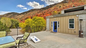 A deck with outdoor furniture, a blue door, and a view of autumn-colored trees against a hillside. - Lava Hot Springs Studio w/ Views, Walk to River (Lava Hot Springs)