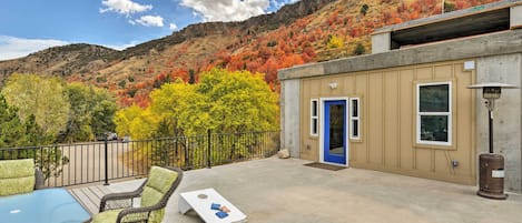 A deck with outdoor furniture, a blue door, and a view of autumn-colored trees against a hillside.