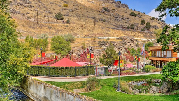 A landscaped area with a river, a bridge, and a building with a red roof. - Lava Hot Springs Studio w/ Views, Walk to River (Lava Hot Springs)