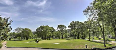 Un campo de golf con un green bien cuidado, un búnker de arena y cielo despejado.
