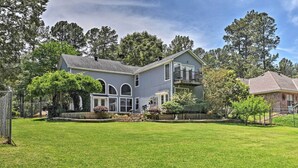 A two-story house with a large front lawn, a covered porch, and a garage. - Cozy Lakefront Benton Home ~ 20 Mi to Shreveport! (Benton)