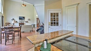 A modern kitchen with a granite countertop, a built-in stove, and a dining area with wooden chairs and a table. - Cozy Lakefront Benton Home ~ 20 Mi to Shreveport! (Benton)