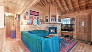 A cabin interior with a wooden interior, a fireplace, a television, and a sofa.