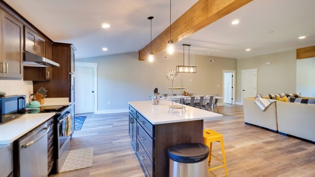 A spacious kitchen with a central island, wooden beams, and modern appliances. - Scenic Home on 20-acre Farm: Families Welcome (Cleveland)