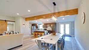 A modern kitchen with wooden beams, a dining area with a long table and chairs, and a living room with a sofa and a coffee table. - Scenic Home on 20-acre Farm: Families Welcome (Cleveland)
