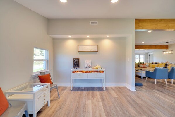A modern living room with a white console table, a blue sofa set, and a wooden ceiling beam.