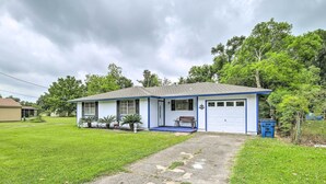 Ein eingeschossiges Haus mit blauer Fassade, einer Veranda und einer Garage.