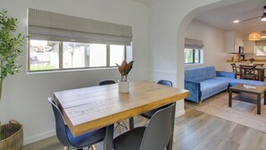 A modern living room with a wooden dining table, blue sofa, and a kitchen area in the background. - Walk to Papago Park: Condo w/ Community Perks! (Scottsdale)