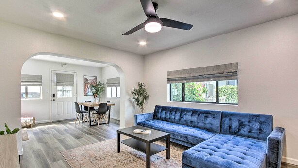 A spacious living room with a blue sofa, a coffee table, and a dining area with a table and chairs. - Walk to Papago Park: Condo w/ Community Perks! (Scottsdale)