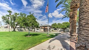 A well-maintained grassy area with a flagpole, palm trees, and a covered pavilion. - Walk to Papago Park: Condo w/ Community Perks! (Scottsdale)