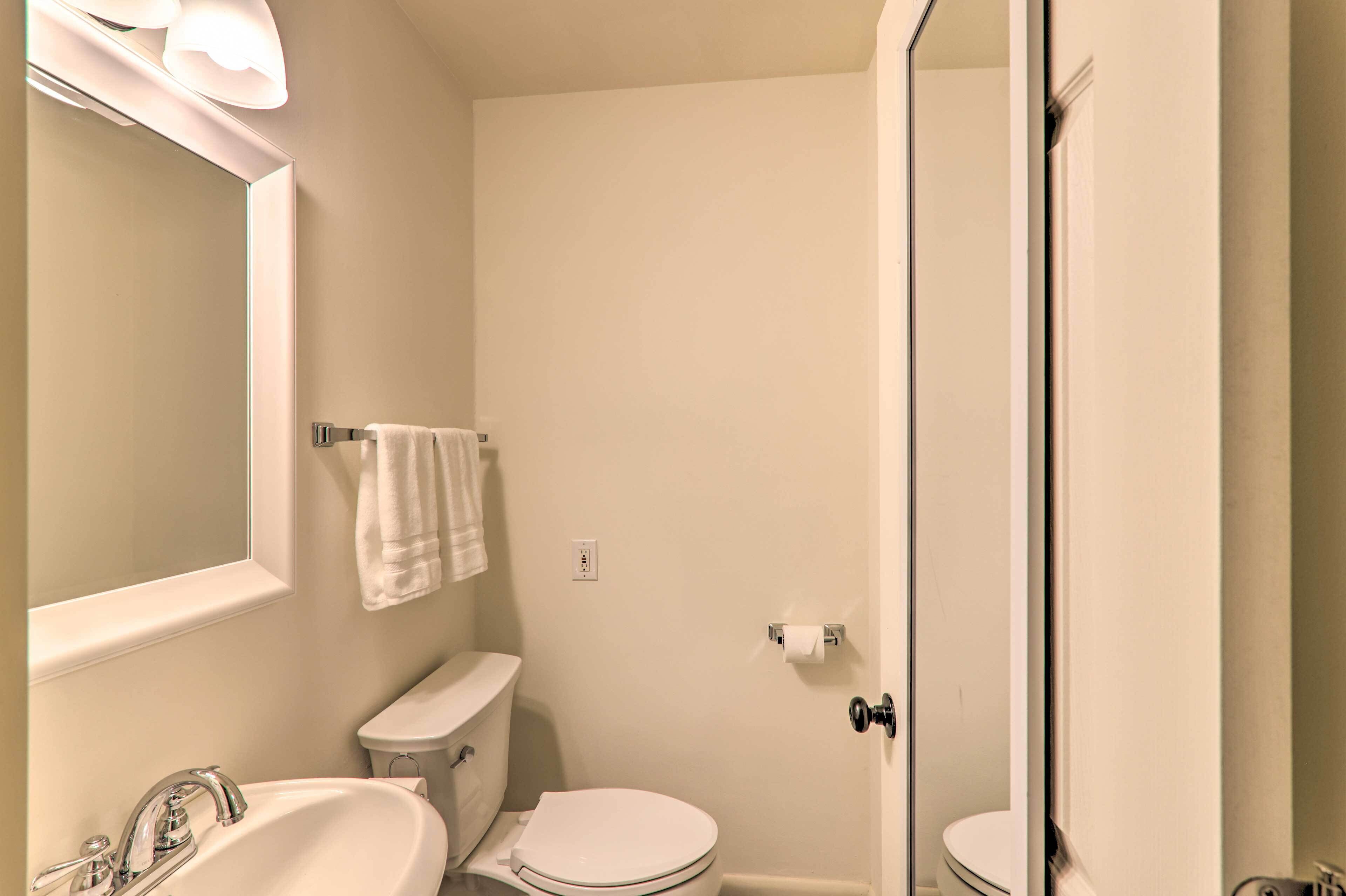 A small, clean bathroom with a sink, toilet, and a mirror.
