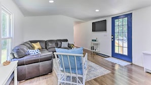 A living room with a dark leather sofa, a white rocking chair, and a blue door. - Wallkill Riverfront Retreat: Canoe & Relax! (New Paltz)