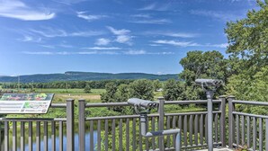 A riverside walkway with a metal railing, a binocular stand, and a visitor information board. - Wallkill Riverfront Retreat: Canoe & Relax! (New Paltz)