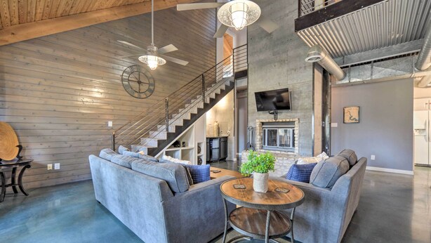 A spacious living area with a gray sectional sofa, a round wooden coffee table, and a staircase leading to an upper level. - Dog-friendly Kingsland Rental on Lake Lbj! (Kingsland)