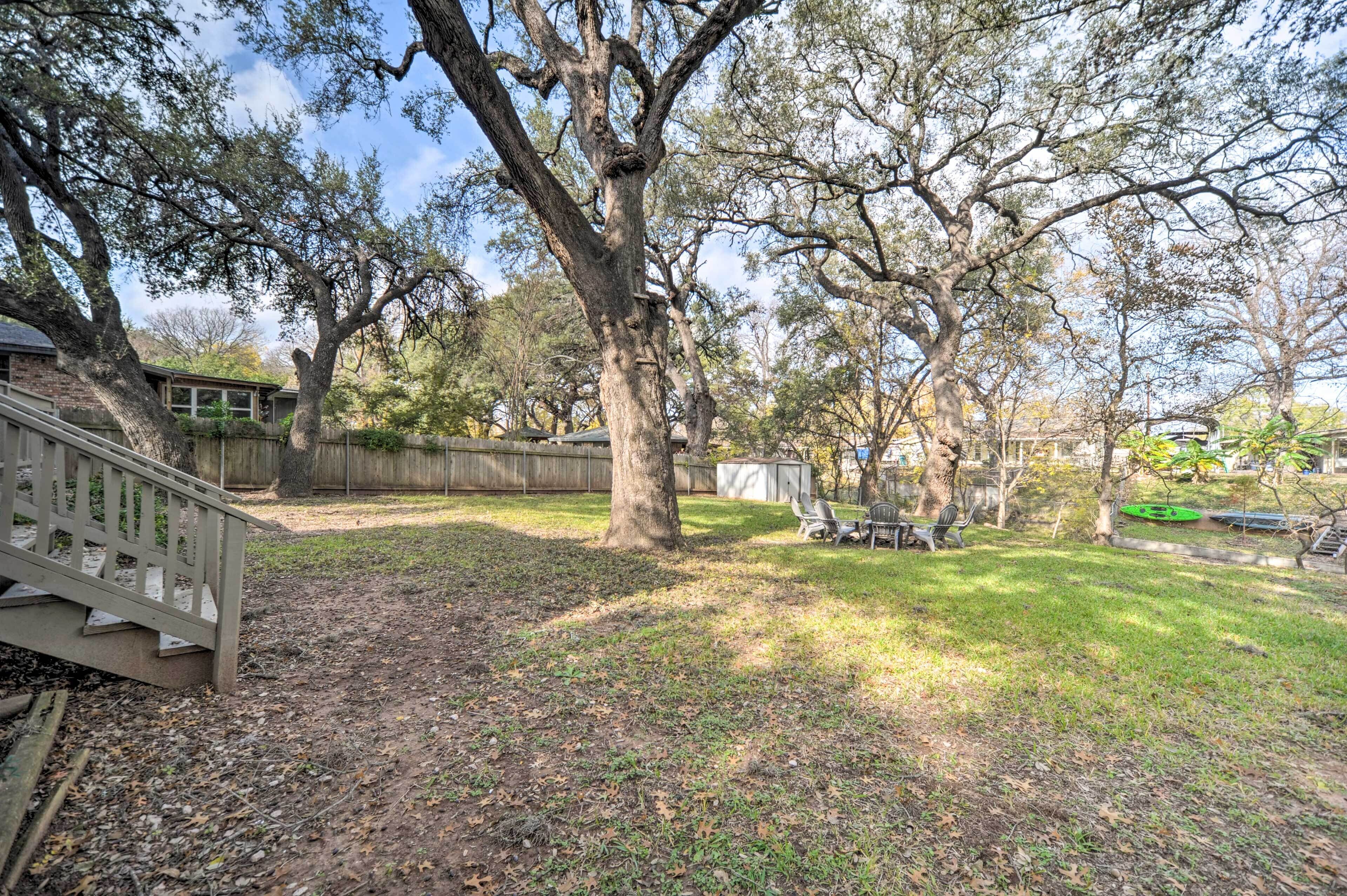 A backyard with a wooden deck, a large tree, and a fenced area.