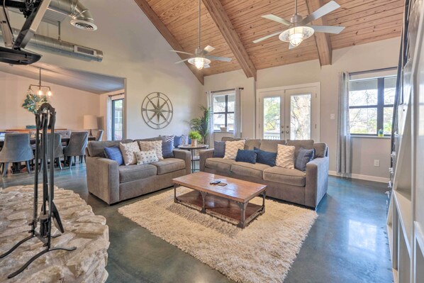 A spacious living room with two grey sofas, a wooden coffee table, and a stone accent piece. - Dog-friendly Kingsland Rental on Lake Lbj! (Kingsland)