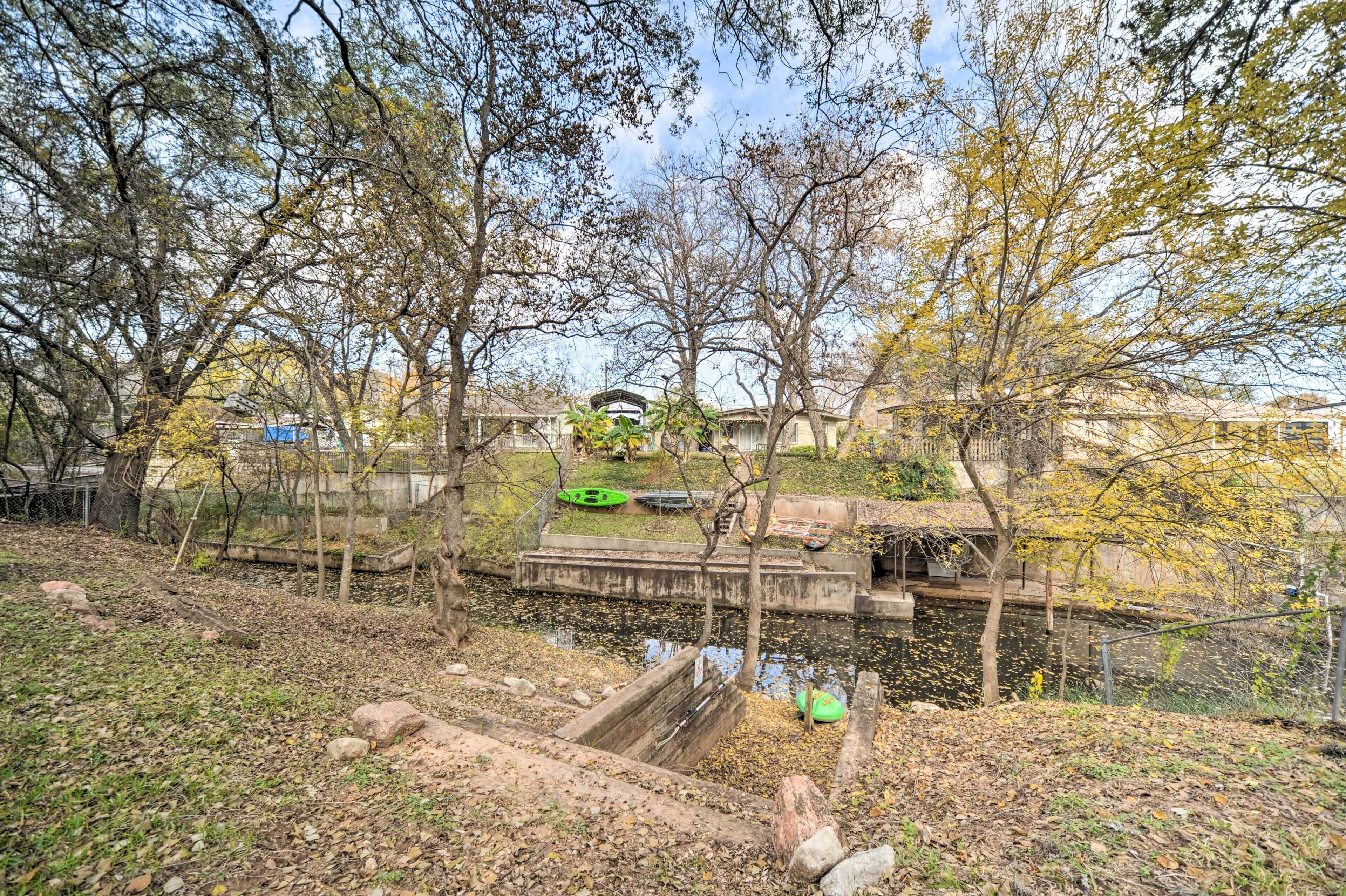 Un parc avec un étang, des arbres et un petit pont.