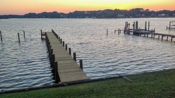 A wooden pier extending into calm water, surrounded by a grassy area.