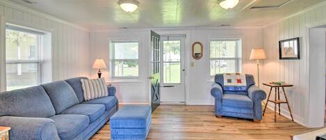 A room with a blue sofa, a matching ottoman, a blue armchair, and a small wooden table.