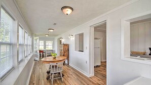 A spacious hallway with wooden flooring, white walls, and a dining area with a round table and chairs. - Romantic Waterfront Abode With Patio & Dock! (Deltaville)
