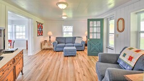 A cozy living room with a blue sofa, matching ottoman, and a green door. - Romantic Waterfront Abode With Patio & Dock! (Deltaville)