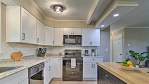 A kitchen with white cabinets, a stainless steel microwave, a built-in oven, and a wooden countertop. - Deck & Gas Grill: Modern East Stroudsburg Home! (East Stroudsburg)