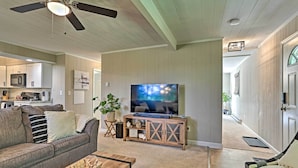 A living room with a sofa, coffee table, TV, and a wooden entertainment center. - Deck & Gas Grill: Modern East Stroudsburg Home! (East Stroudsburg)