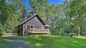 A cabin with a wooden deck and a covered outdoor seating area. - Deck & Gas Grill: Modern East Stroudsburg Home! (East Stroudsburg)