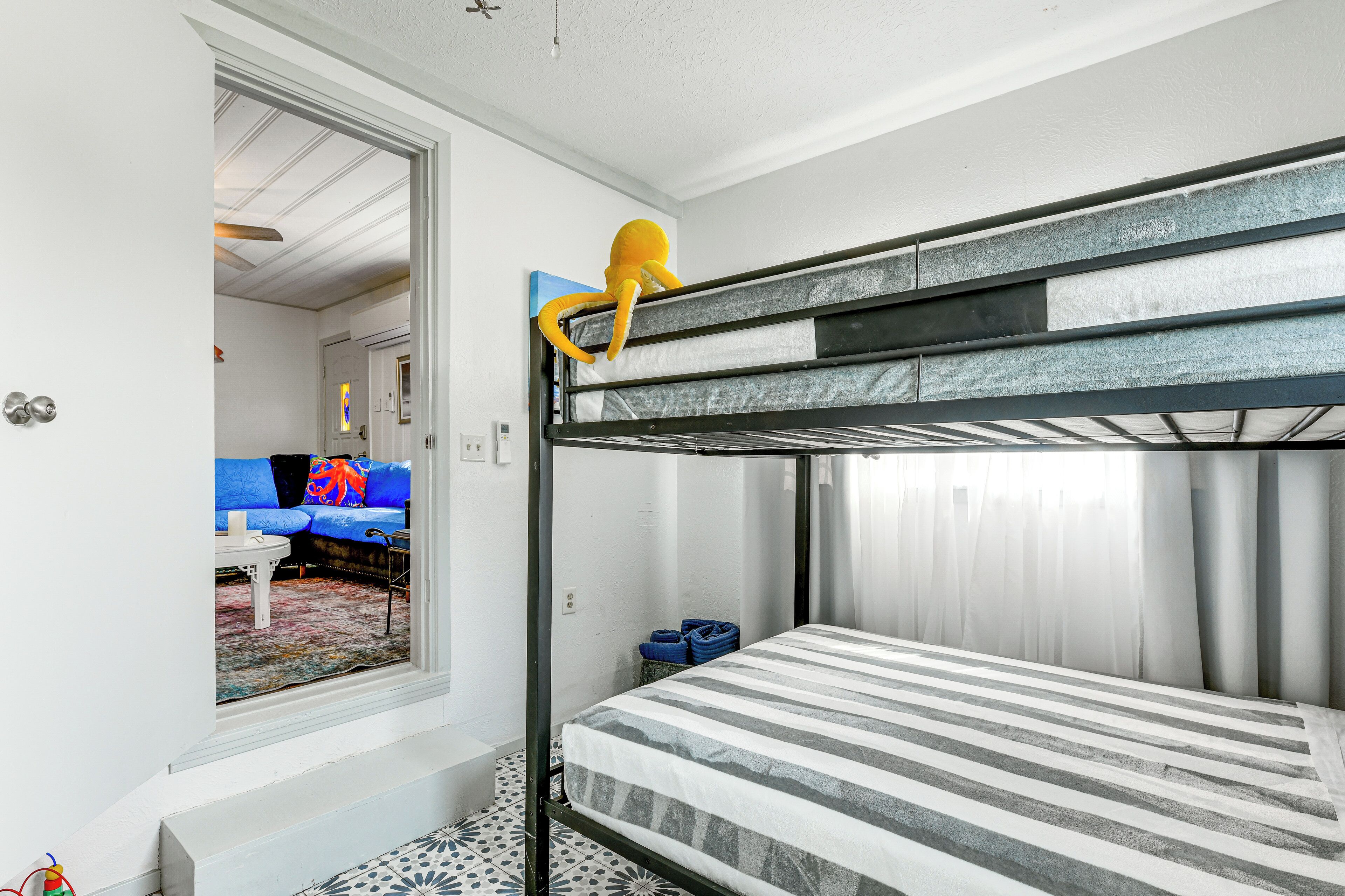 Habitación con literas, un sofá y suelo estampado.