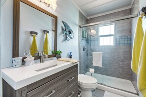 A bathroom with a white sink, dark wooden vanity, a glass shower enclosure, and a large mirror. - Cozy Cottage w/ Patio < 2 Mi to Rockport Beach! (Rockport)