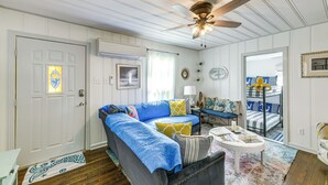 A room with a ceiling fan, a sofa, a coffee table, and a bunk bed.