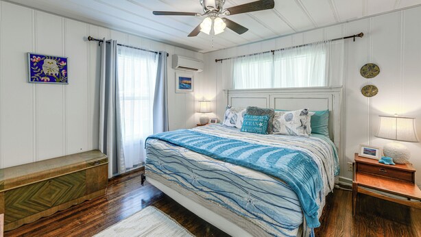 A bedroom with a bed, a nightstand, a ceiling fan, and a window with curtains.