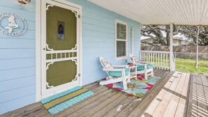 A porch with a wooden floor, a white railing, and a colorful rug.