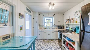 A kitchen with white cabinets, a blue table, and a patterned floor.