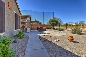 Un giardino con patio, posti a sedere all'aperto, un barbecue e un'area giochi recintata.