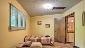 A bedroom with two beds, a window with blinds, a door, and a carpeted floor.