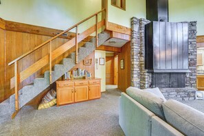 A staircase with wooden railings and carpeted steps, a stone fireplace, and a wooden cabinet with books. - Rogers Cabin w/ Direct Access to Beaver Lake! (Garfield)