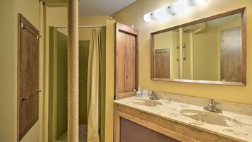 A bathroom with a wooden vanity, a large mirror, and a shower curtain.