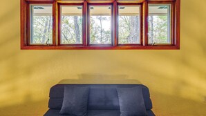 A room with a large window, a sofa, and a wall with a textured finish.