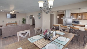 Een ruime woonkamer met een grote bank, een eettafel voor vier personen en een keukenhoek met moderne apparatuur.
