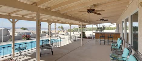 Un espacio al aire libre cubierto con piscina, asientos y bar.