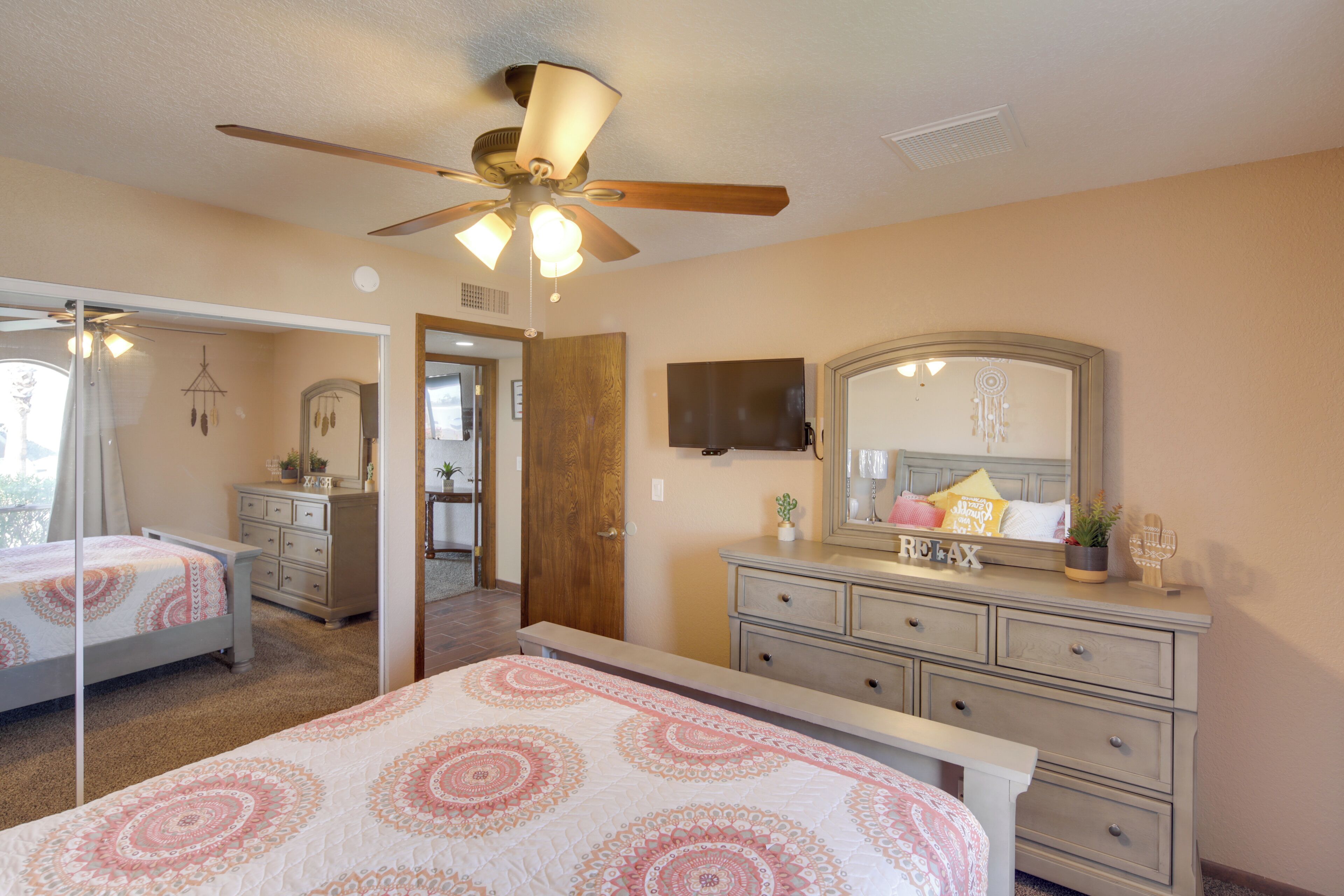 A bedroom with two beds, a ceiling fan, a dresser, and a mirror.