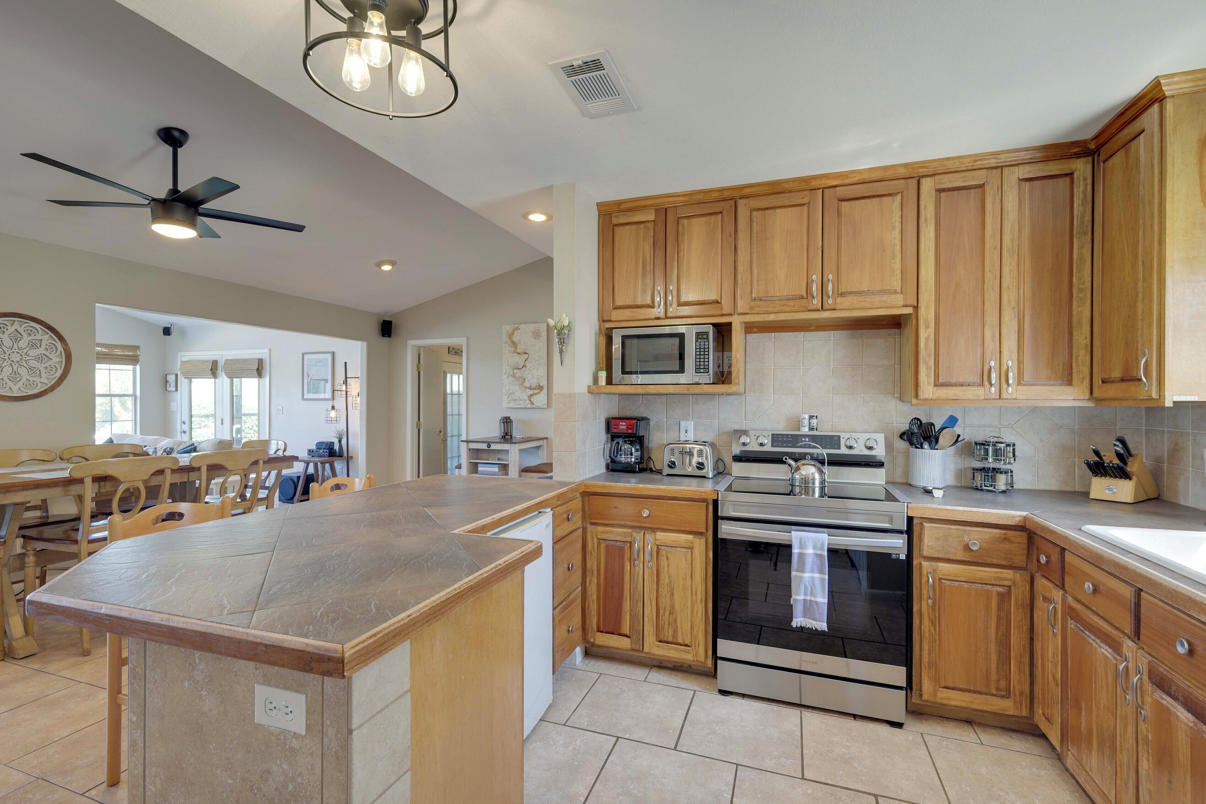 A modern kitchen with wooden cabinets, a central island, and built-in appliances.