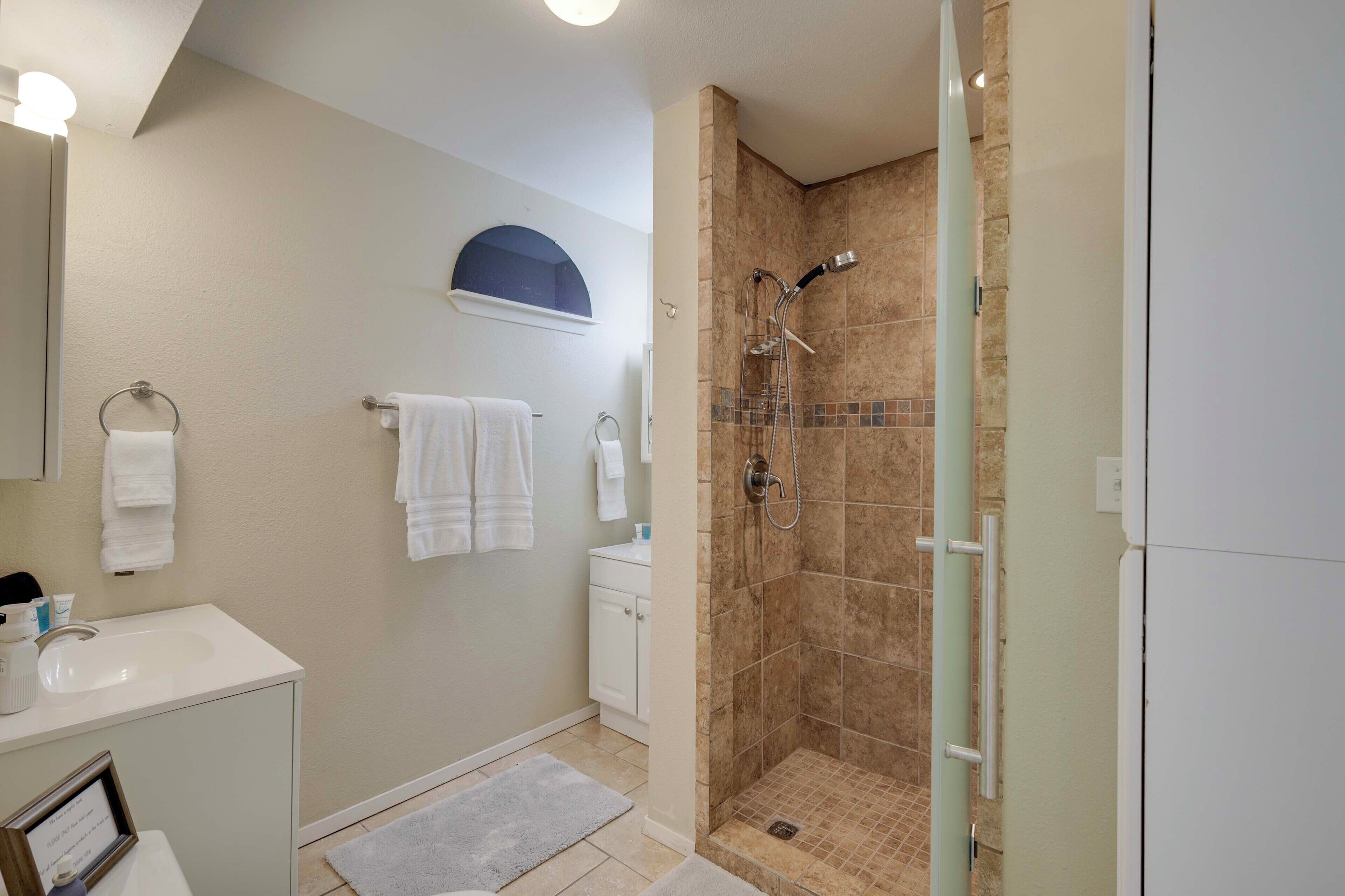 A modern bathroom with a shower, a sink, and a mirror.