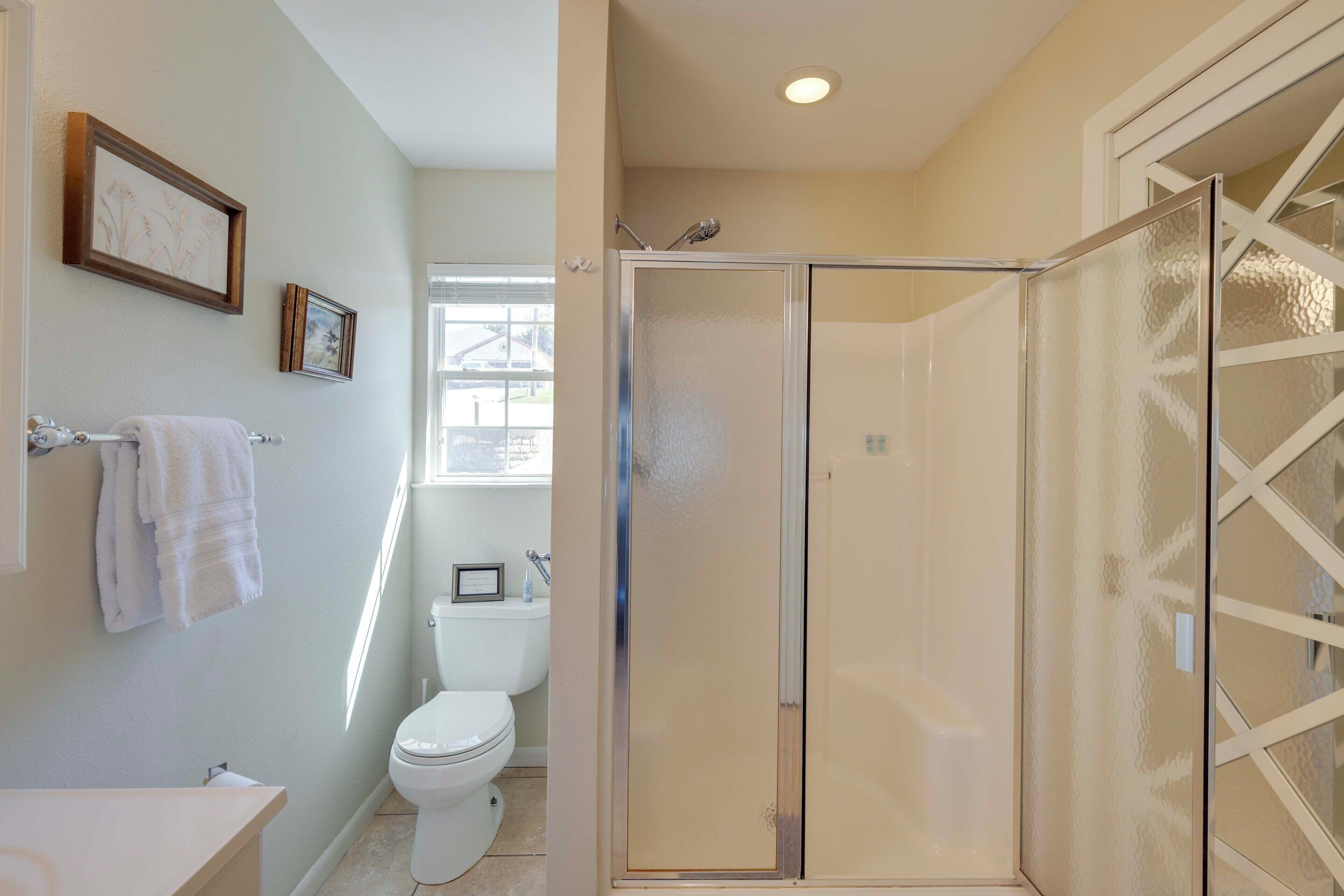 A bathroom with a toilet, a shower with frosted glass doors, and a sink with a towel rack.