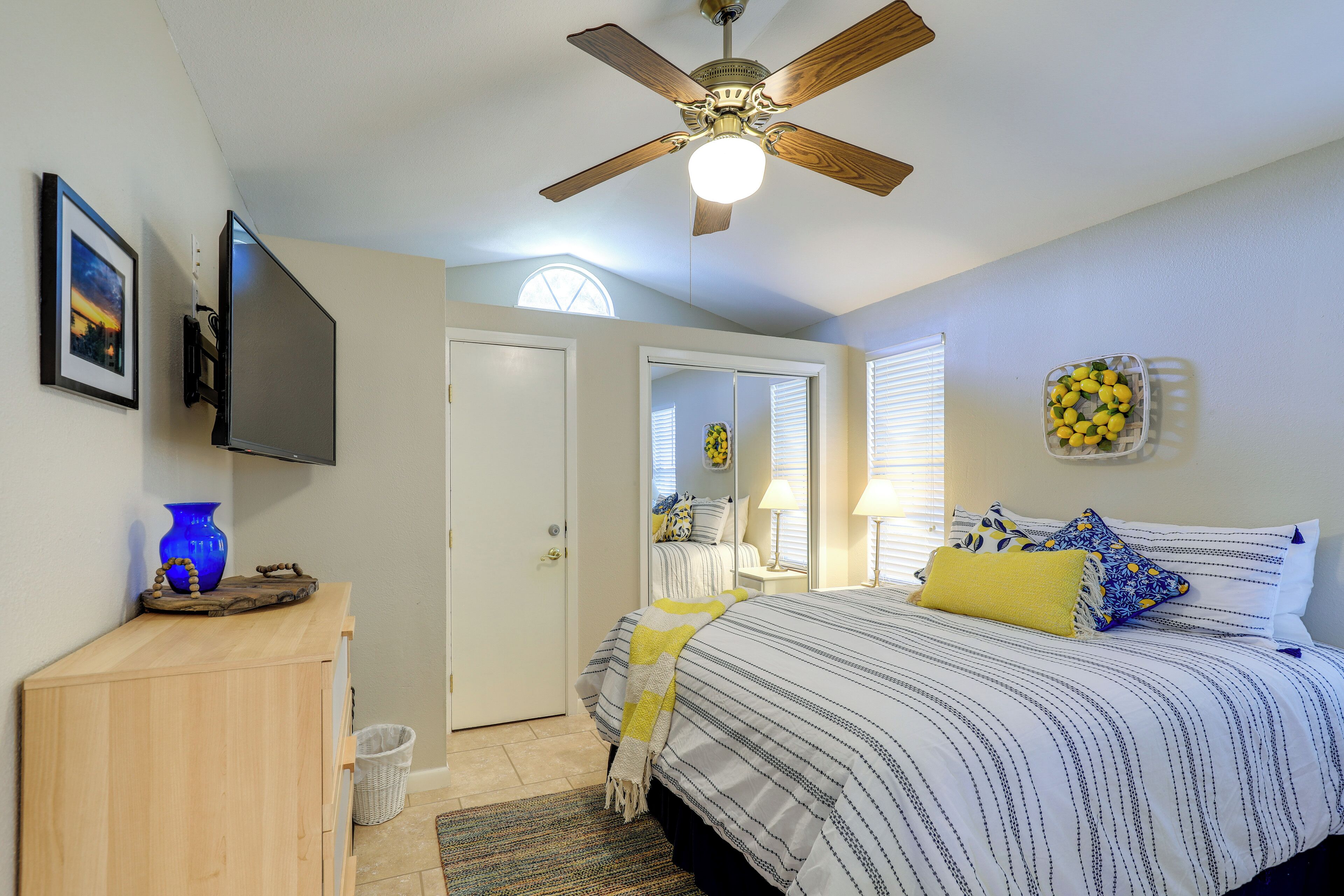 Une chambre à coucher avec un lit, un ventilateur de plafond, une télévision et une fenêtre.