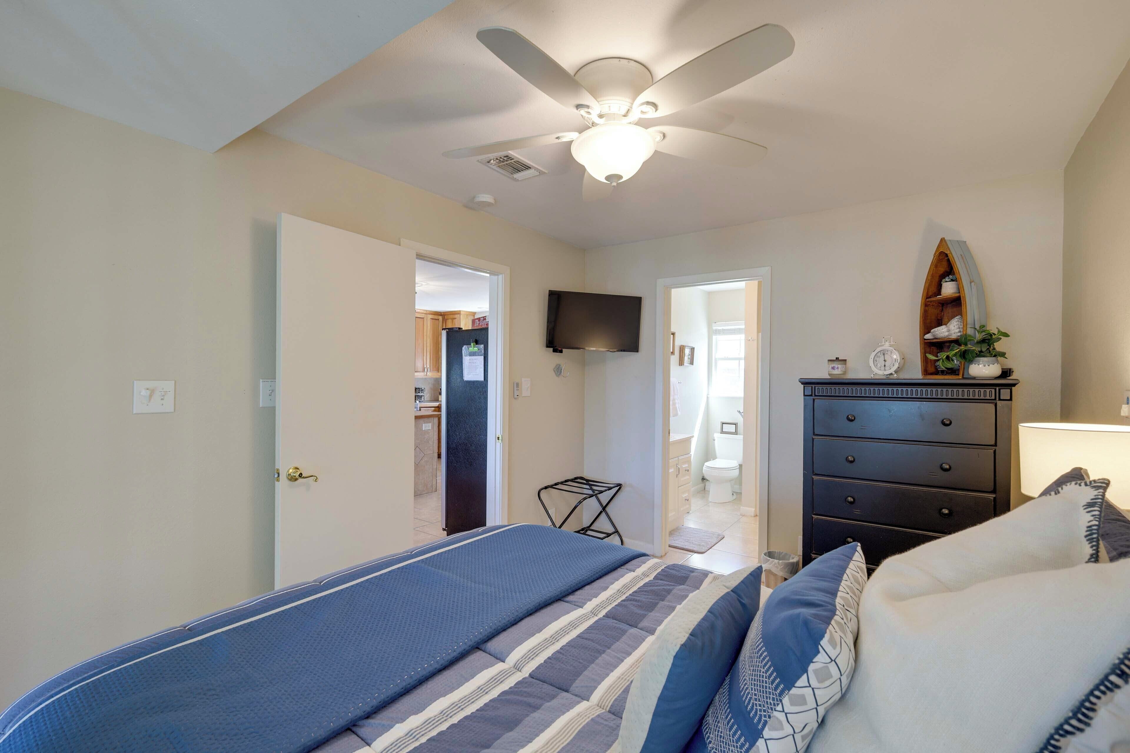 A bedroom with a bed, dresser, and a ceiling fan.